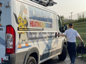 Iceberg Heating & Cooling truck photographed from the side with a technician closing the truck door and walking away..