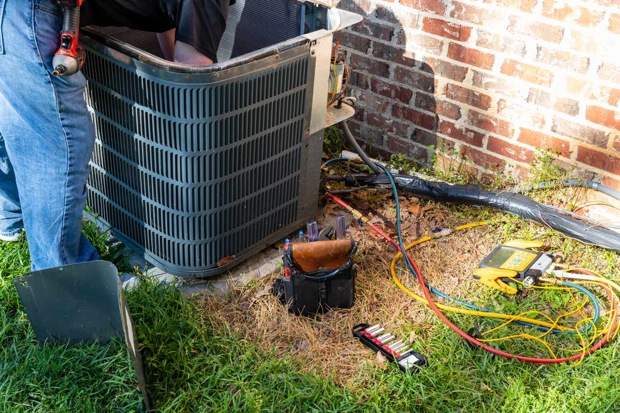 HVAC technician performing maintenance on an outdoor AC unit