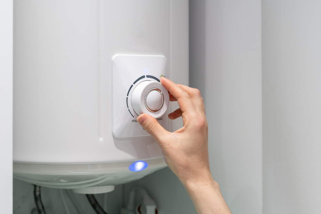 Michigan homeowner's hand on the temperature knob of a boiler