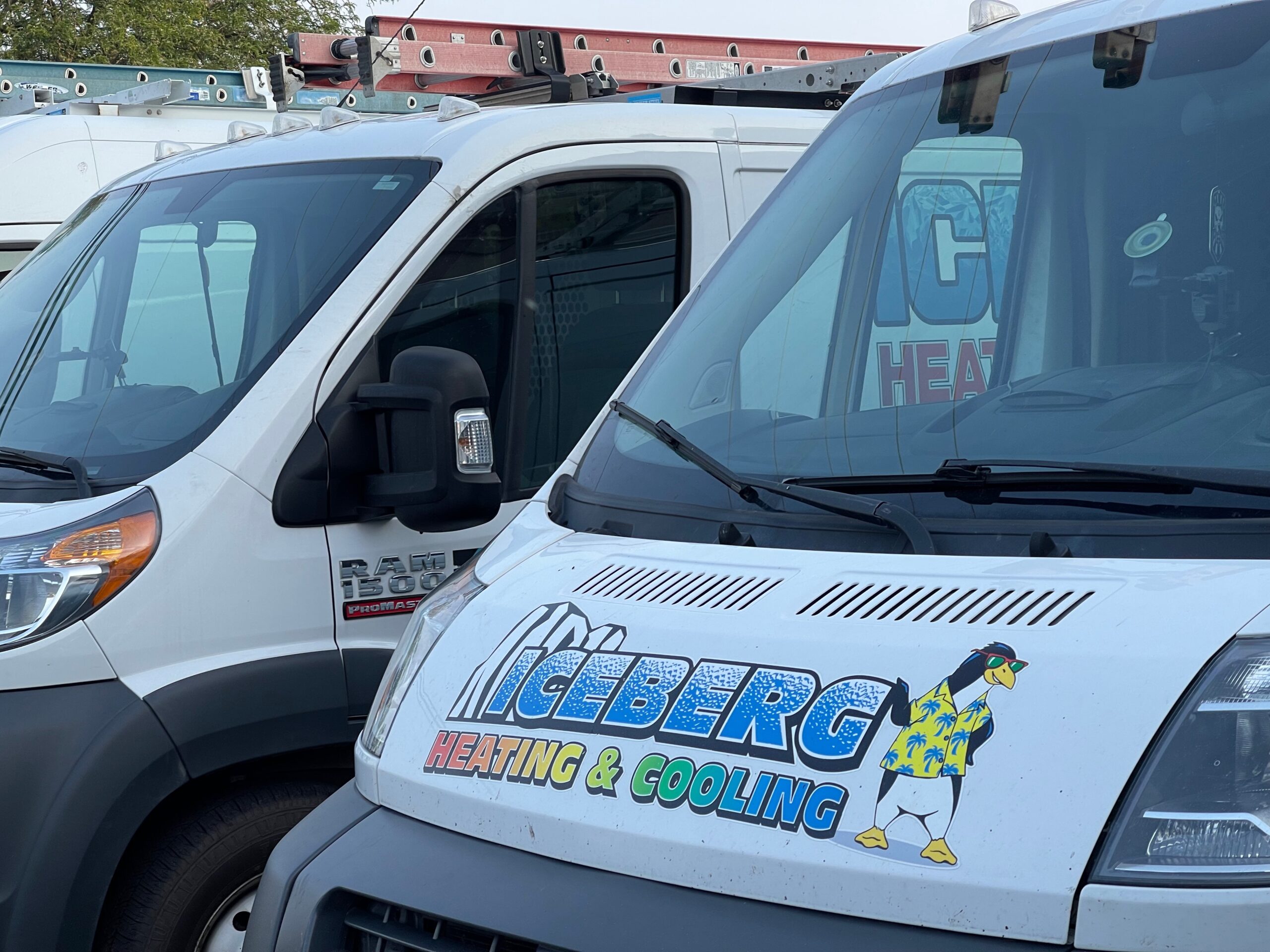 Line of Iceberg Heating & Cooling trucks with branded logo on the hood