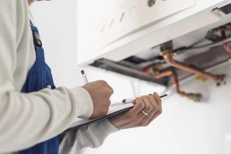 Technician standing in front of a boiler with a checklist on a clipboard