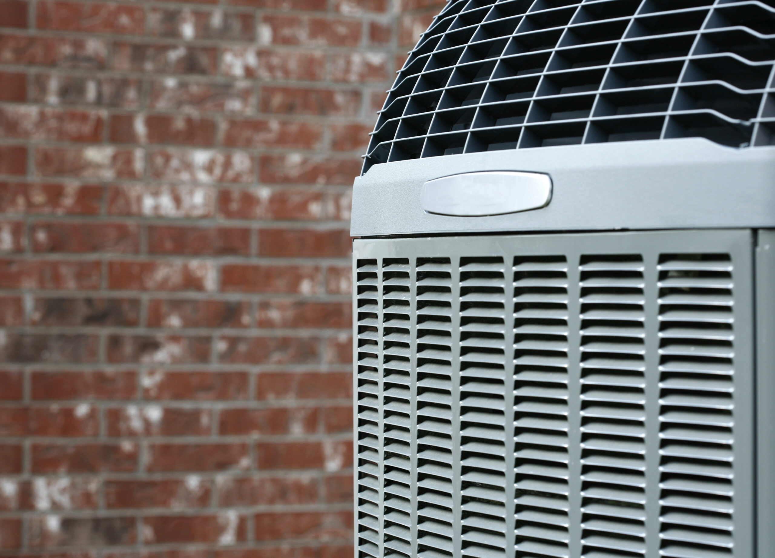 Close-up of an air conditioning unit against a residential brick wall